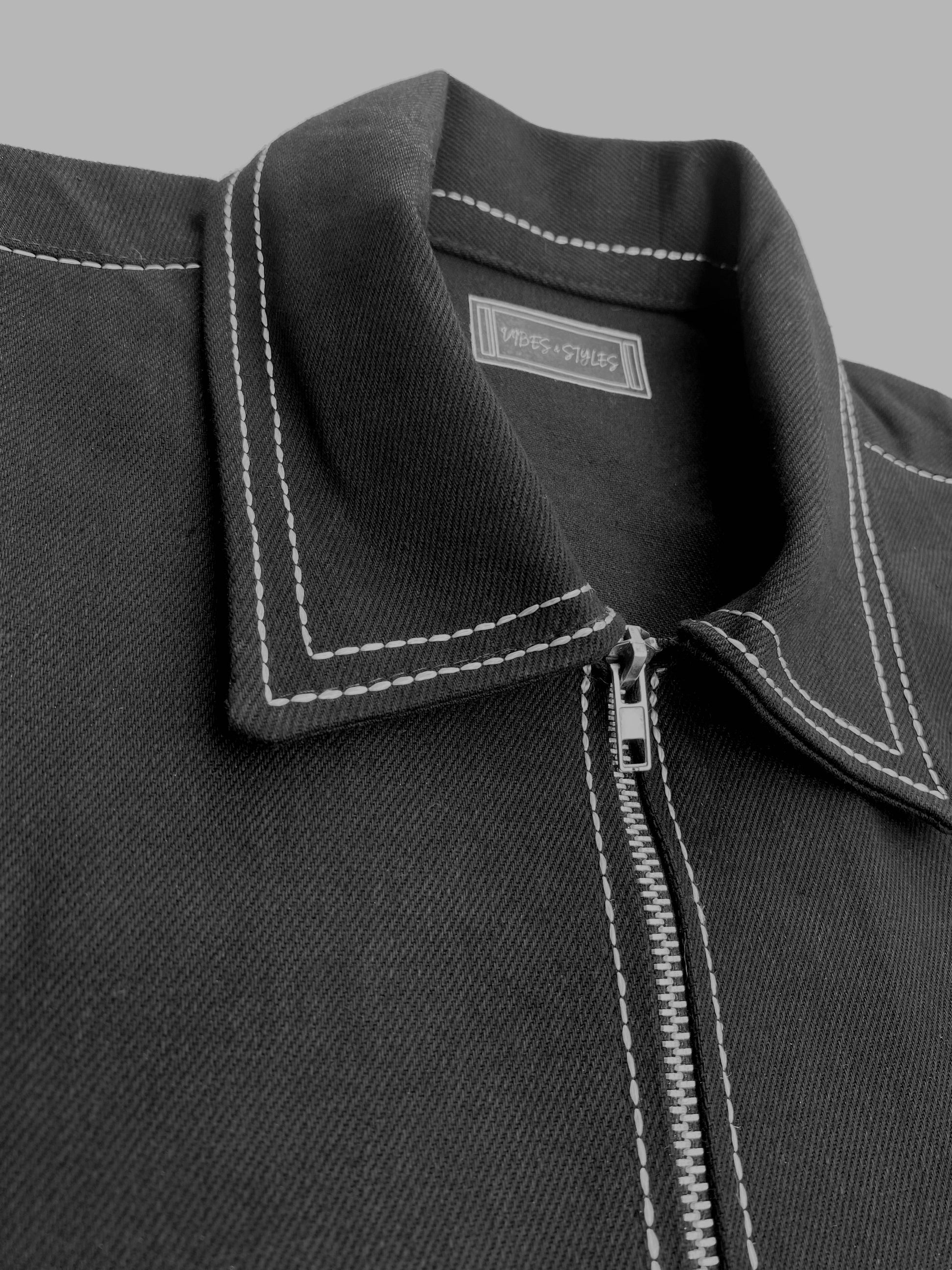 Close-up of a black jacket collar with white stitching on a gray background