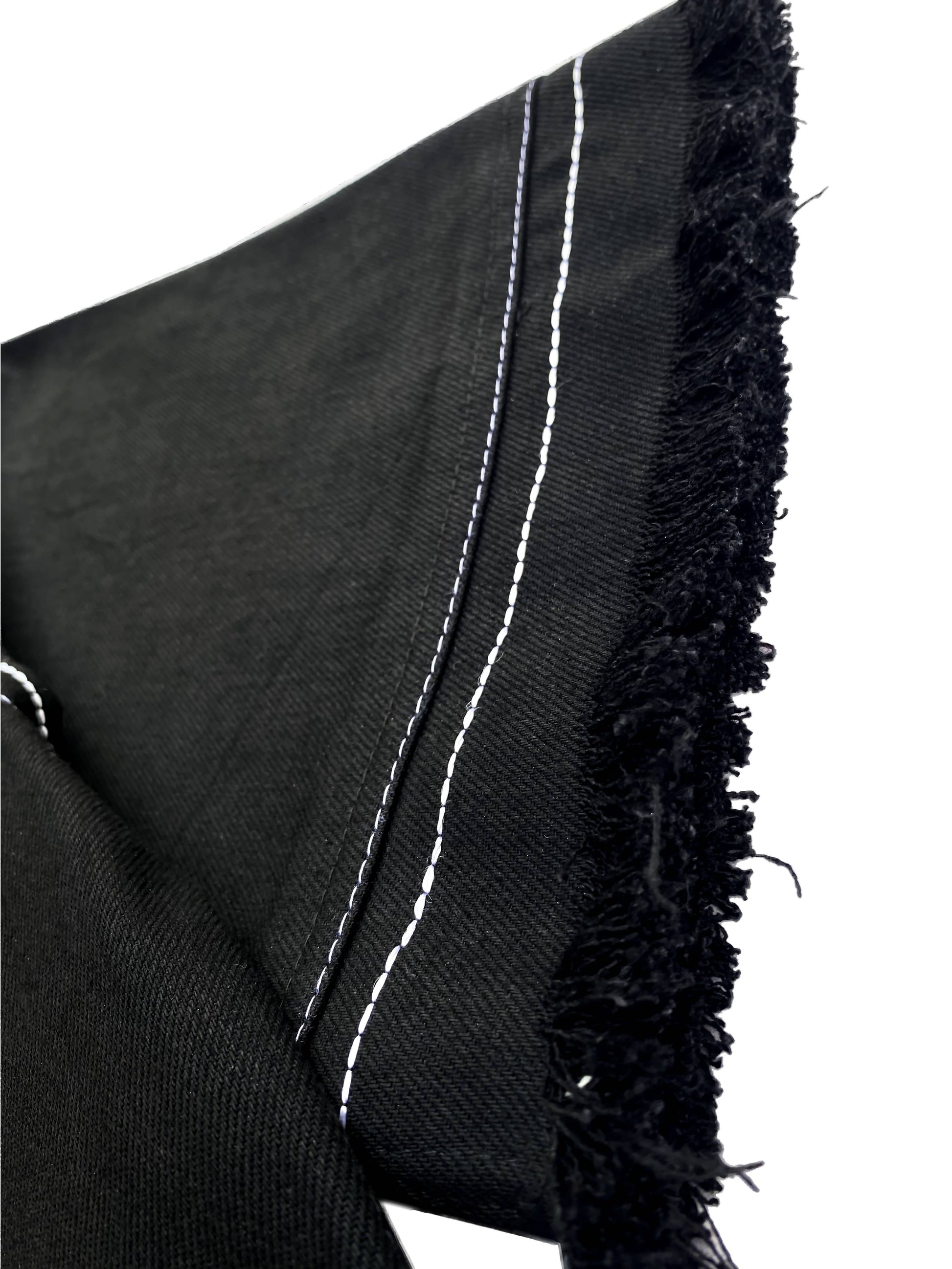 Black fabric with white stitching and frayed edges on a white background