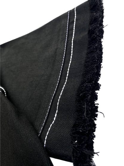 Black fabric with white stitching and frayed edges on a white background