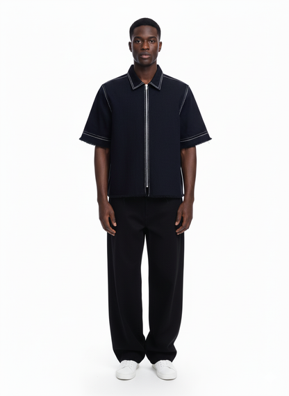 Man wearing a black zip-up shirt and pants on a white background